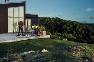 A person using a power washer to clean a patio in a scenic outdoor setting.