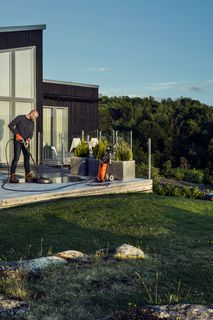 A person using a power washer to clean a patio in a scenic outdoor setting.