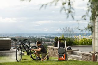 Husqvarna PW 350. Une personne nettoie un vélo à l’aide d’un tuyau d’arrosage dans un jardin.