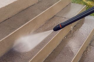 A high-pressure water jet cleaning outdoor stone steps.
