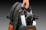 Close-up of a person holding a pressure washer by its handle, showcasing its compact design.