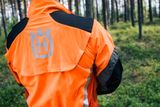 Person wearing Husqvarna work gear in a forest setting.