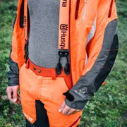 Person wearing Husqvarna work gear in a forest setting.