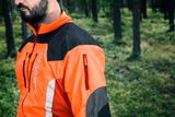 Person facing away wearing Husqvarna work jacket in a forest setting.