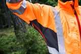 Особа в робочому спорядженні підвищеної видимості в лісі.