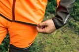 森の中で作業具のウエストバンドを調整する人物のクローズアップ。