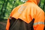 Persona che indossa abbigliamento da lavoro con logo Husqvarna in un ambiente forestale.
