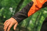 Primo piano del braccio di una persona che indossa attrezzature da lavoro in un ambiente forestale.