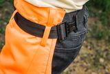 Close-up of a person wearing work trousers with a black belt.