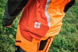 Person wearing work gear with a visible cross symbol on the pocket.