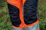 Close-up of Husqvarna chainsaw trousers with reflective strips in a forest setting.