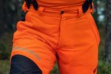 Person wearing Husqvarna chainsaw trousers in a forest setting.