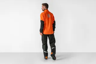 Persona de espaldas vestida con pantalones y equipo de trabajo Husqvarna para motosierra.