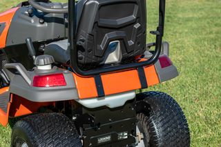 Rear view of a ride-on lawn mower on a grassy area.