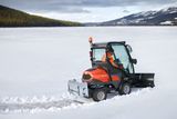 Un véhicule de déneigement déneigeant un vaste paysage enneigé.