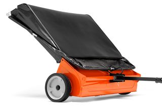 Side view of a lawn sweeper with a large collection bag and tow bar.