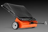 Side view of a lawn sweeper with a tow bar and collection bag.