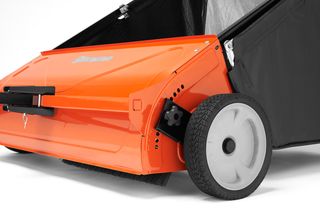 Side view of a Husqvarna lawn sweeper with a focus on its wheel and brush mechanism.