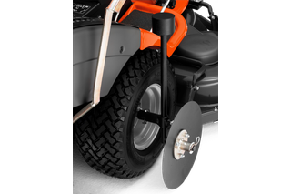 Detailní pohled na kolo sekačky na trávu s připojeným bočním ochranným diskem.