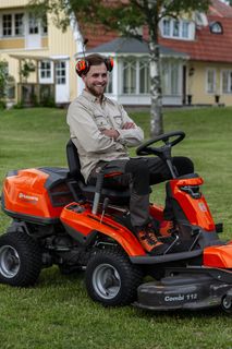 Una persona seduta su un trattorino tagliaerba in un giardino.