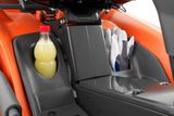 Gros plan du compartiment de rangement d’une tondeuse autoportée avec une bouteille de boisson et des gants.