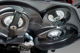 Close-up view of the underside of a lawn mower showing its blades and cutting deck.