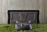 Robotic lawn mower on grass with a charging station in the background.