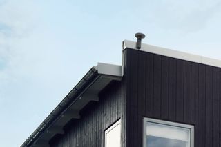Hörnutsikt över ett modernt hus med träpanel och ett fönster.