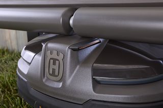 Close-up view of a Husqvarna robotic lawn mower under a shelter.
