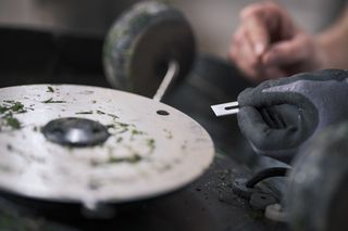Close-up of a person sharpening a blade on a grinding wheel.