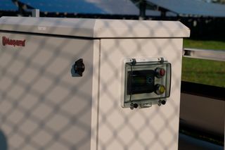 A Husqvarna control unit outdoors, with solar panels visible in the background.