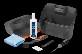 Draufsicht eines Husqvarna Reinigungssets mit Sprühflasche, Tuch, Bürsten und Schraubendreher.