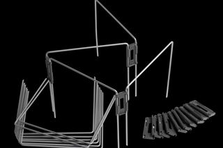 Draufsicht auf Metallrahmen und schwarze Bauteile, die auf einer weißen Fläche angeordnet sind.