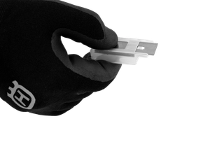 Close-up of a gloved hand holding a small rectangular blade with a mounting slot.