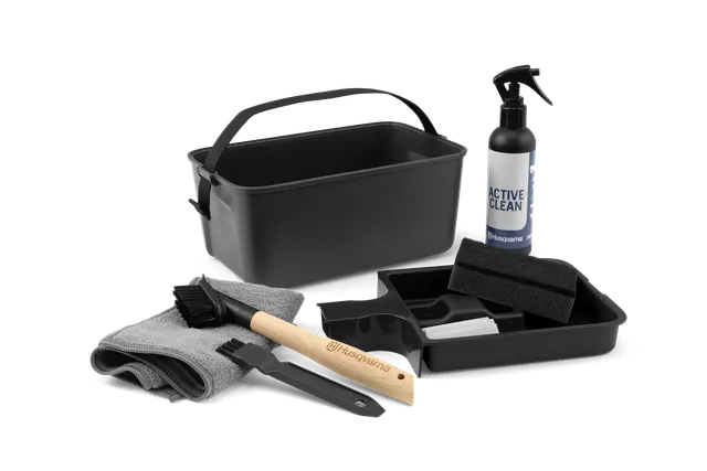 Husqvarna rengöringskit med sprayflaska, borstar, svamp, trasa och bricka.