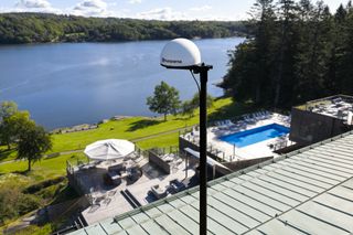 Une vue panoramique sur une zone au bord d’un lac avec une piscine et un patio, vue depuis un toit.