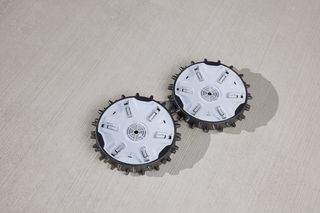 Top view of two robotic lawn mower blades on a concrete surface.