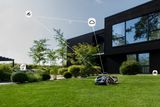 Robotic lawn mower operating in a garden with a satellite signal icon overlay.