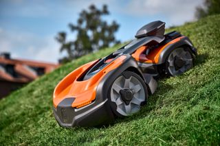 Robot tondeuse fonctionnant sur une pente herbeuse dans un jardin.