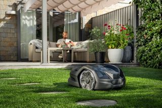 Robotic lawn mower operating on a well-maintained lawn in a garden setting.