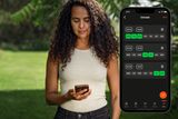 En person som håller i en smartphone i en trädgård med ett schemagränssnitt för mobilapp som visas.