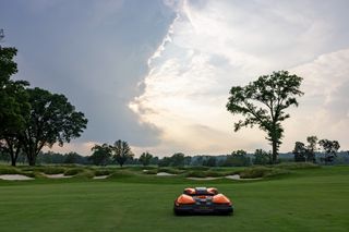 Tondeuse à gazon robotisée fonctionnant sur un terrain de golf avec une toile de fond panoramique.