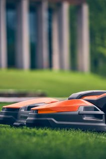 Mähroboter auf einem gepflegten Rasen in der Nähe eines modernen Gebäudes.