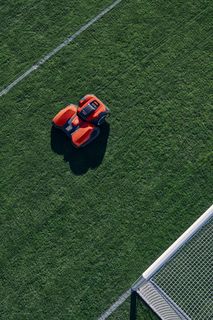 Robot tondeuse utilisé sur un terrain de football.