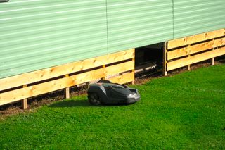 Robotic lawn mower operating on a grassy area next to a building.