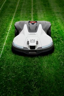 Robotyczna kosiarka pracująca na zadbanym trawniku.