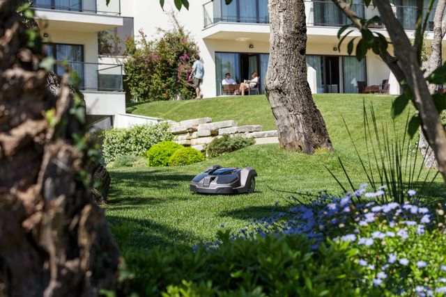 Robot tondeuse fonctionnant sur une pelouse bien entretenue dans un jardin résidentiel.