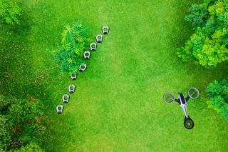 Luftaufnahme mehrerer Mähroboter auf einer Wiese mit Bäumen.
