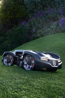 Robot cortacésped funcionando en una pendiente cubierta de hierba en un jardín.
