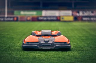 Robot cortacésped funcionando en un campo de deportes.